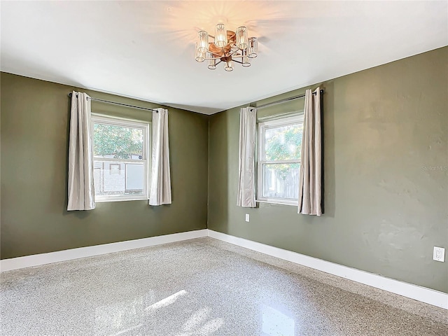 spare room featuring a wealth of natural light and a chandelier