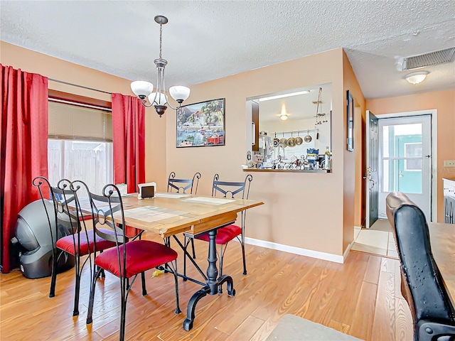 dining room featuring light hardwood / wood-style floors, a textured ceiling, and a chandelier