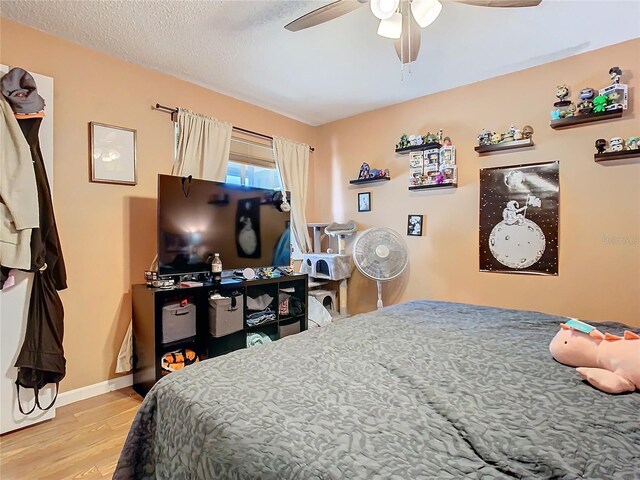 bedroom with ceiling fan, light hardwood / wood-style floors, and a textured ceiling