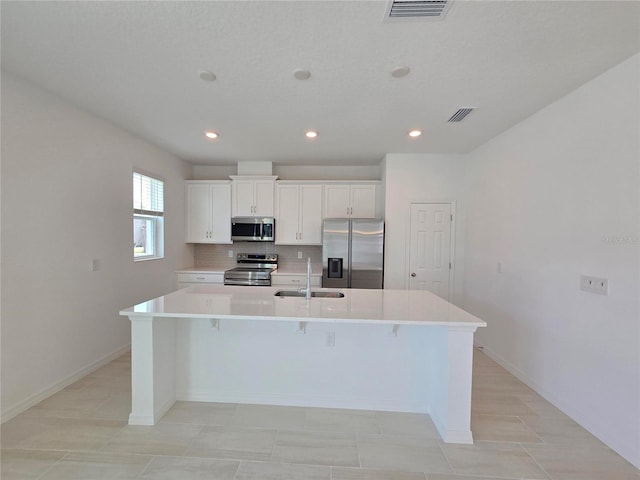1162 Happy Forest Loop, Deland, FL 32720 - kitchen featuring stainless steel appliances, a kitchen island with sink, a sink, decorative backsplash, and white cabinetry