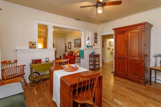 dining room featuring ceiling fan, light wood-type flooring, crown molding, and decorative columns