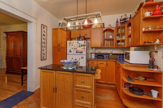 kitchen with a kitchen island, white appliances, hanging light fixtures, and light hardwood / wood-style flooring