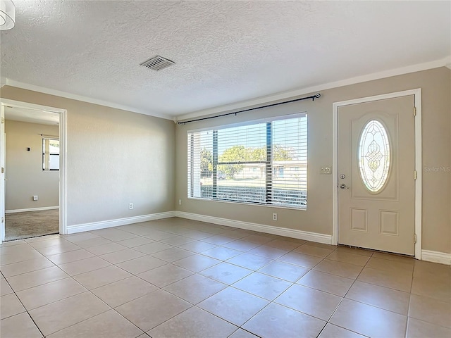 tiled foyer with a textured ceiling, a wealth of natural light, and ornamental molding