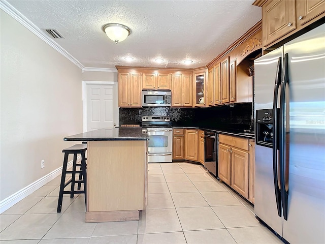 kitchen with appliances with stainless steel finishes, a kitchen breakfast bar, backsplash, crown molding, and a center island