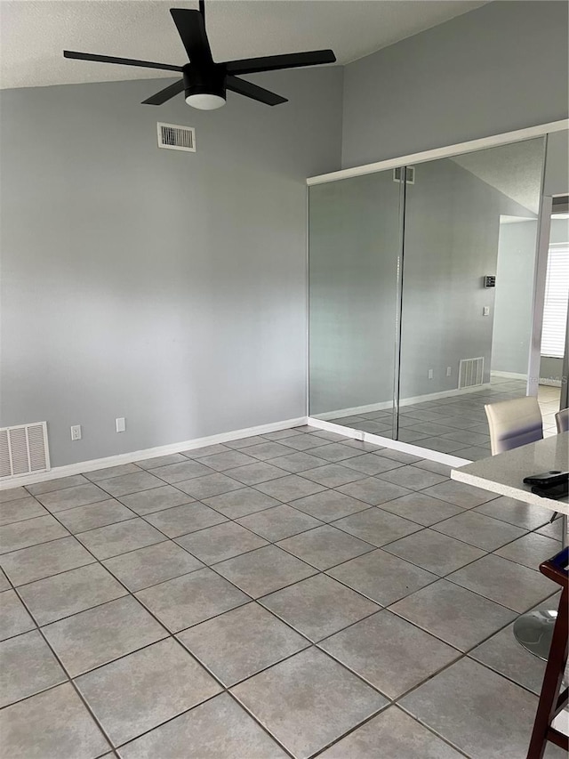 unfurnished room featuring ceiling fan, light tile patterned flooring, a textured ceiling, and vaulted ceiling