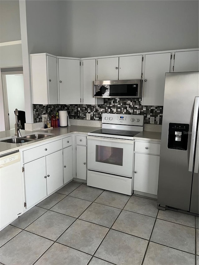 kitchen with backsplash, white cabinets, sink, light tile patterned floors, and appliances with stainless steel finishes