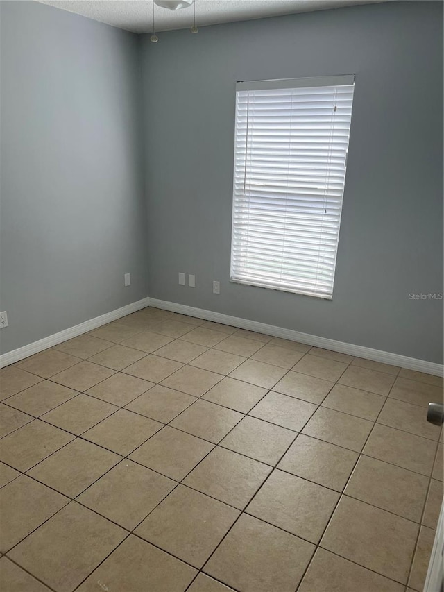 spare room with ceiling fan and light tile patterned flooring