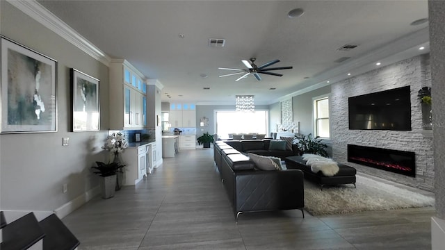 living room featuring a fireplace, ceiling fan, and ornamental molding