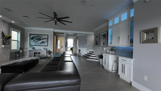 living room with crown molding, ceiling fan, and a healthy amount of sunlight