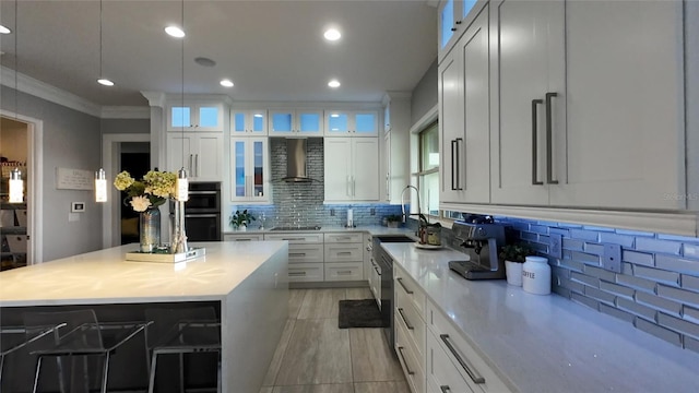 kitchen featuring white cabinetry, wall chimney exhaust hood, decorative light fixtures, and a kitchen island