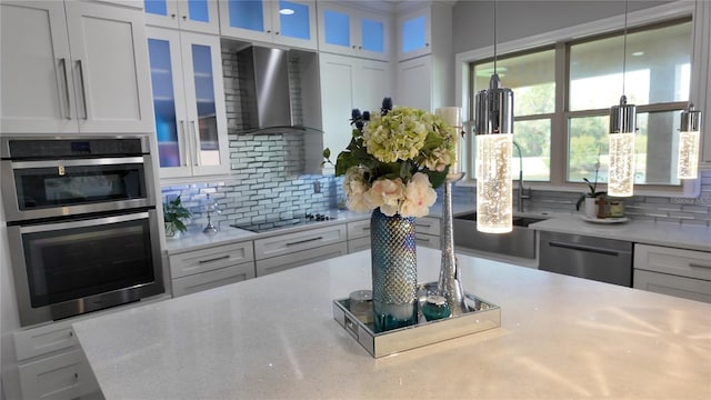 kitchen featuring white cabinets, wall chimney range hood, and appliances with stainless steel finishes