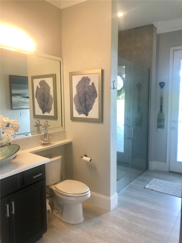 bathroom with vanity, hardwood / wood-style flooring, toilet, ornamental molding, and a shower with shower door