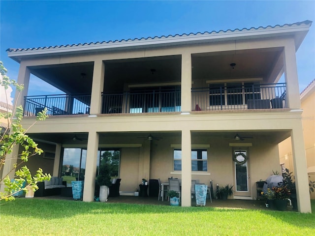 back of property featuring a lawn, ceiling fan, a balcony, and an outdoor living space