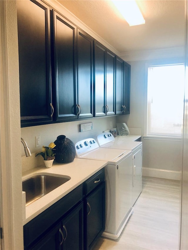 laundry room with separate washer and dryer, sink, cabinets, and light hardwood / wood-style floors