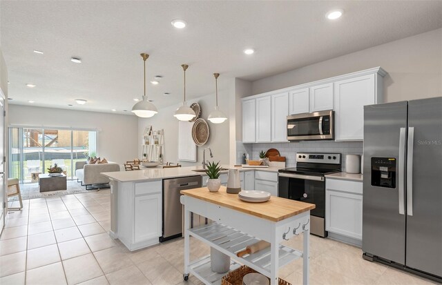 kitchen featuring tasteful backsplash, white cabinetry, pendant lighting, and stainless steel appliances