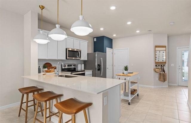 kitchen featuring white cabinetry, stainless steel appliances, backsplash, kitchen peninsula, and decorative light fixtures