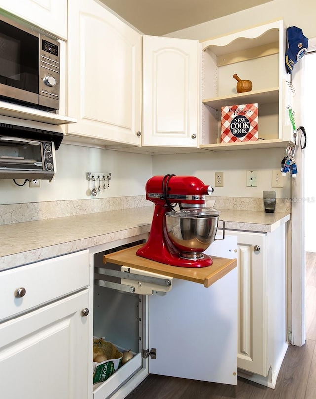 kitchen featuring light countertops, dark wood-style flooring, stainless steel microwave, and white cabinetry