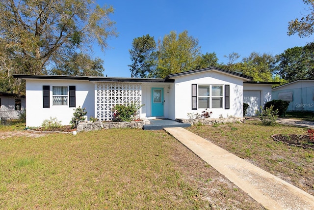 single story home featuring a garage, a front lawn, and stucco siding