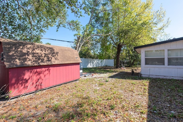 view of yard featuring fence, an outdoor structure, and a storage shed