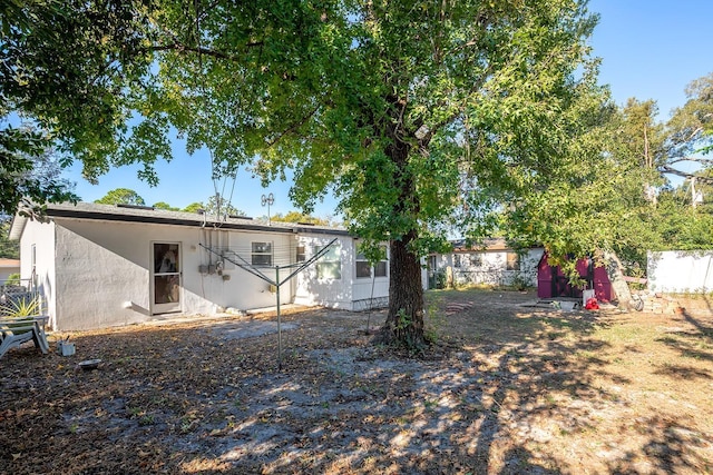 rear view of house with fence and stucco siding