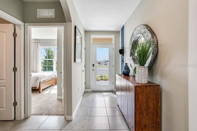 doorway with light tile patterned floors and plenty of natural light