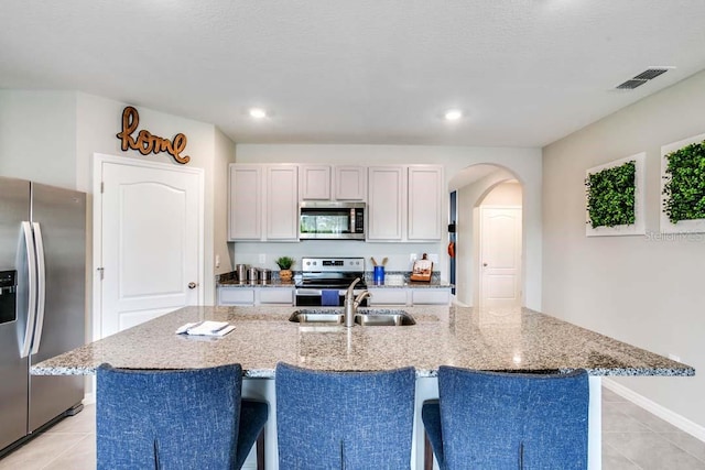 kitchen featuring sink, a center island with sink, white cabinets, and appliances with stainless steel finishes