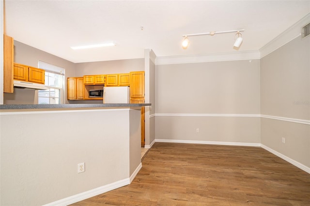 kitchen with kitchen peninsula, track lighting, light hardwood / wood-style floors, crown molding, and white fridge