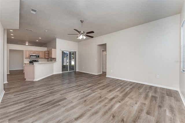 unfurnished living room with ceiling fan, light hardwood / wood-style floors, and a textured ceiling