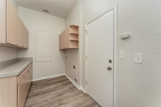 clothes washing area with cabinets, washer hookup, light hardwood / wood-style flooring, and electric dryer hookup