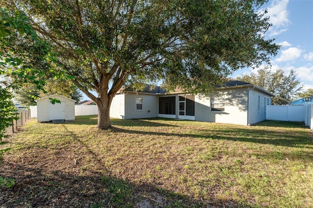 back of house featuring a shed and a lawn