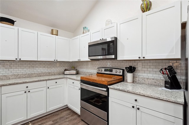 kitchen with tasteful backsplash, white cabinetry, appliances with stainless steel finishes, and vaulted ceiling