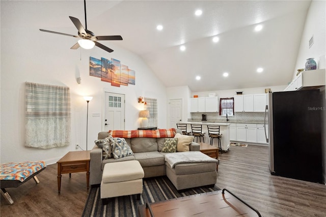 living room featuring ceiling fan, sink, dark wood-type flooring, and vaulted ceiling