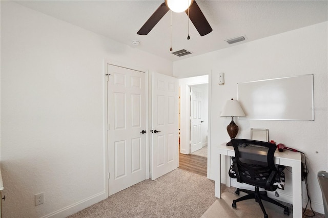 carpeted office space with ceiling fan