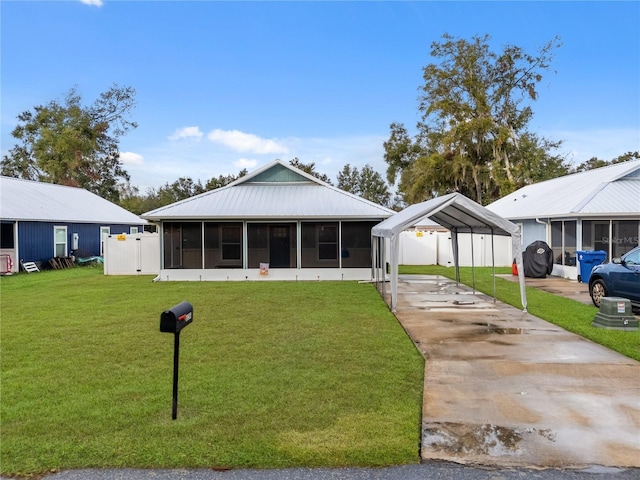 view of front of property featuring a carport, a sunroom, and a front lawn