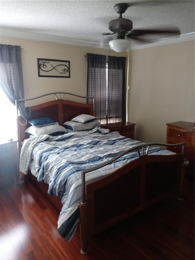 bedroom with a textured ceiling, ceiling fan, crown molding, and dark wood-type flooring