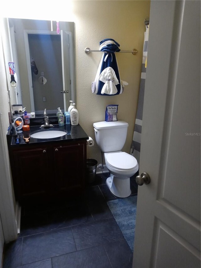 bathroom with vanity, tile patterned floors, curtained shower, and toilet