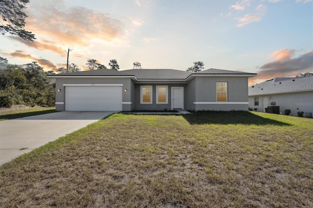 view of front of house featuring a yard, a garage, and central AC unit