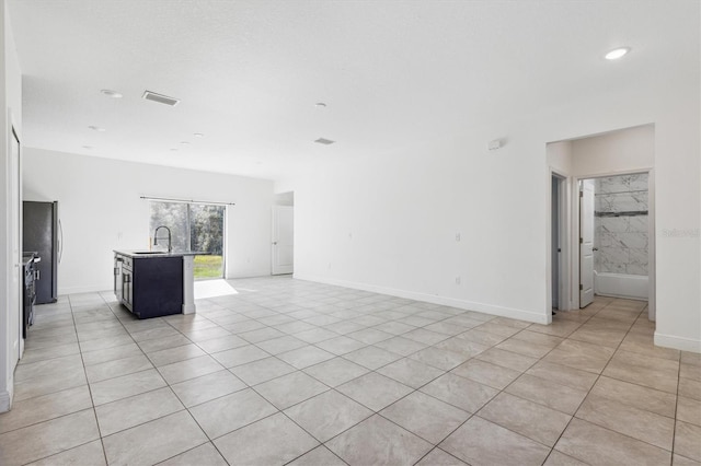 unfurnished living room featuring light tile patterned floors and sink