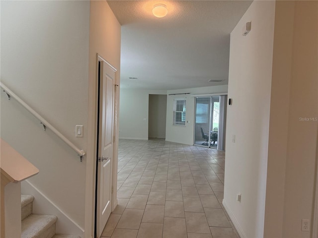 hallway featuring light tile patterned flooring and a textured ceiling