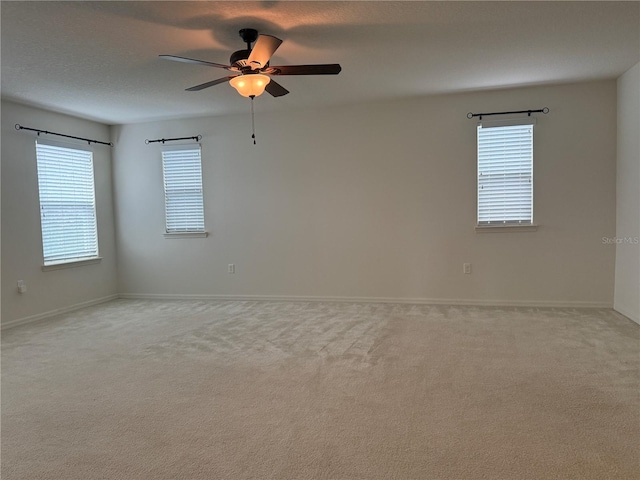 empty room with light carpet, a wealth of natural light, and ceiling fan