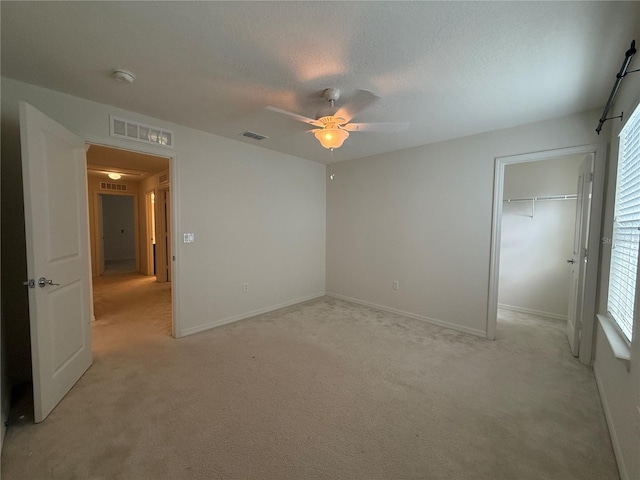 unfurnished room with a textured ceiling, ceiling fan, and light carpet