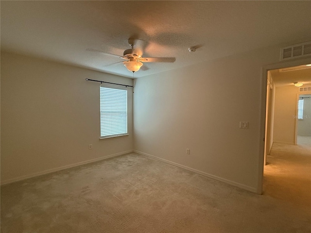 spare room with a wealth of natural light, ceiling fan, and light colored carpet