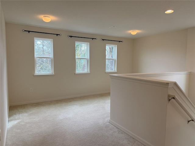 hallway with a wealth of natural light and light colored carpet