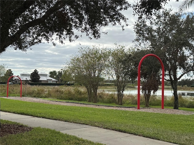 surrounding community with a water view and a yard