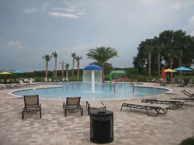 view of swimming pool with pool water feature and a patio