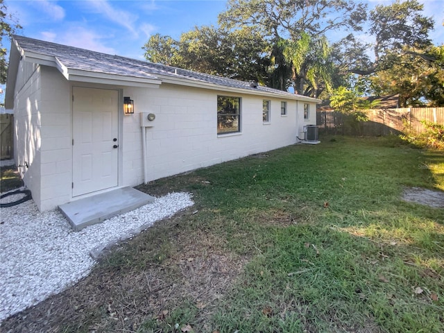 back of property with central air condition unit and a lawn