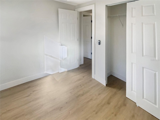 unfurnished bedroom with light hardwood / wood-style flooring and a closet