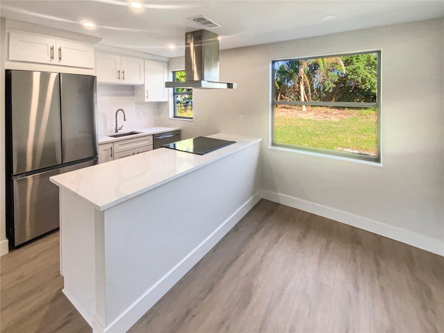 kitchen featuring white cabinets, appliances with stainless steel finishes, extractor fan, and a healthy amount of sunlight