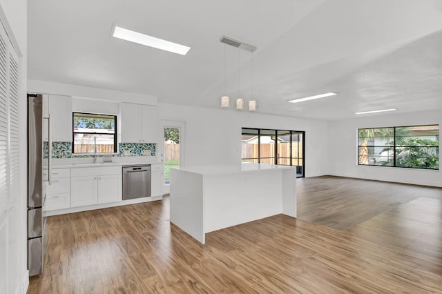 kitchen featuring white cabinetry, tasteful backsplash, light hardwood / wood-style floors, pendant lighting, and appliances with stainless steel finishes