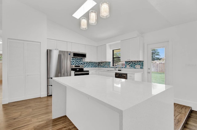 kitchen with a center island, hanging light fixtures, stainless steel appliances, light hardwood / wood-style flooring, and white cabinets